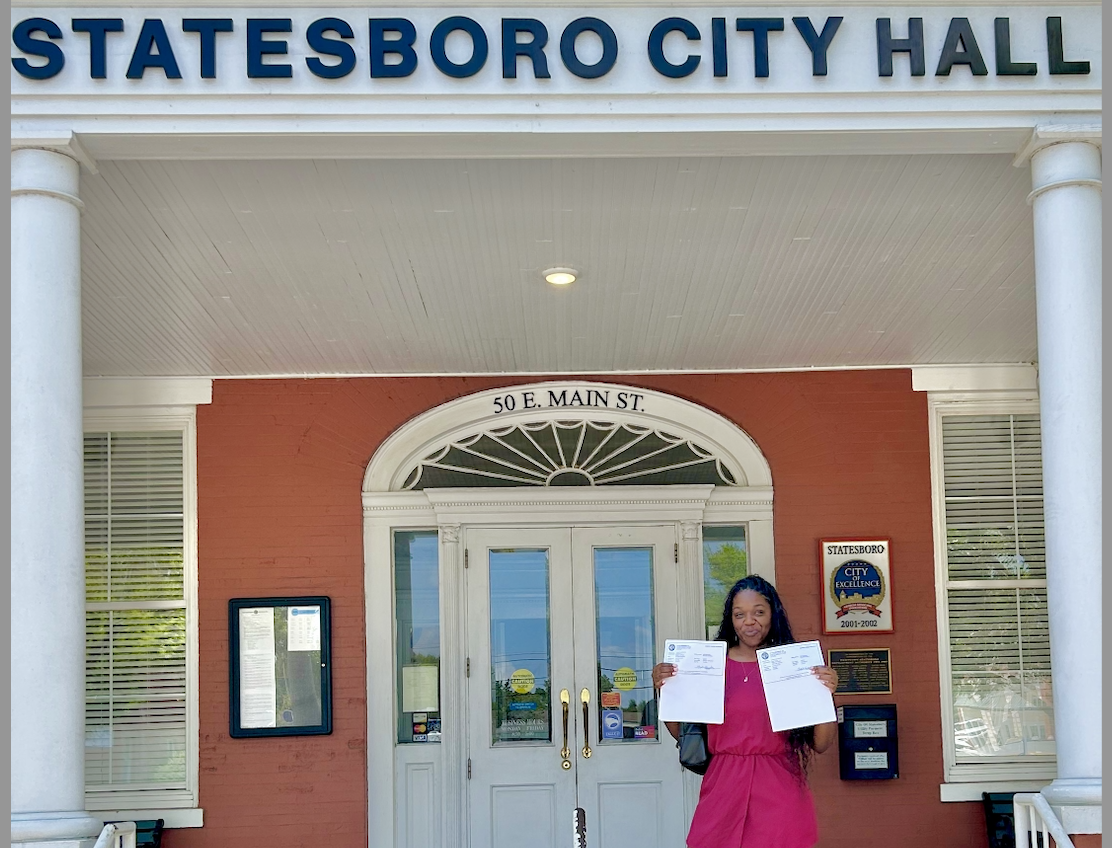 Woman in pink dress at Statesboro City Hall with documents